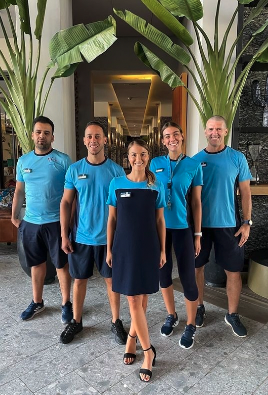 5 Reps stood smiling for the camera with palm trees in the background.